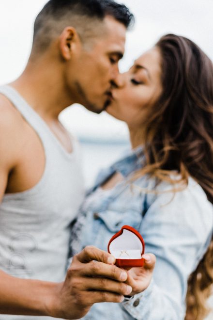 Couple is kissing with an engagement ring